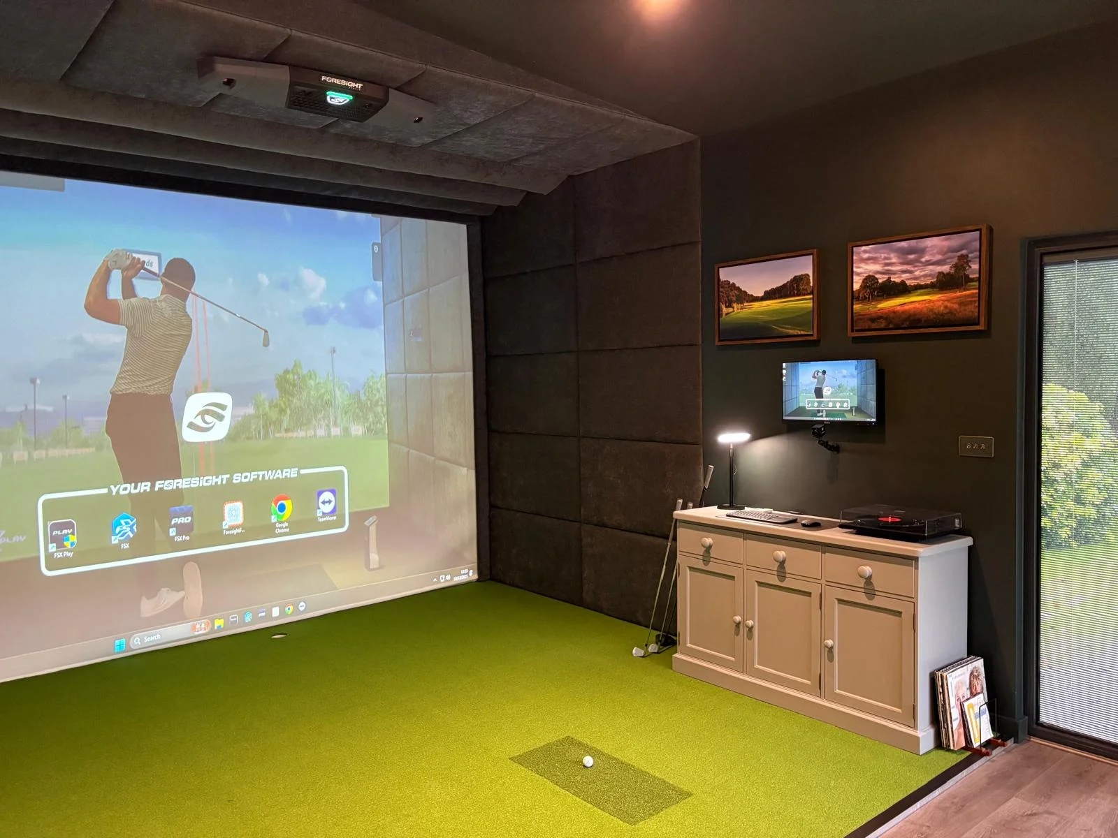 Golf simulator interior — simulator screen and synthetic turf hitting bay