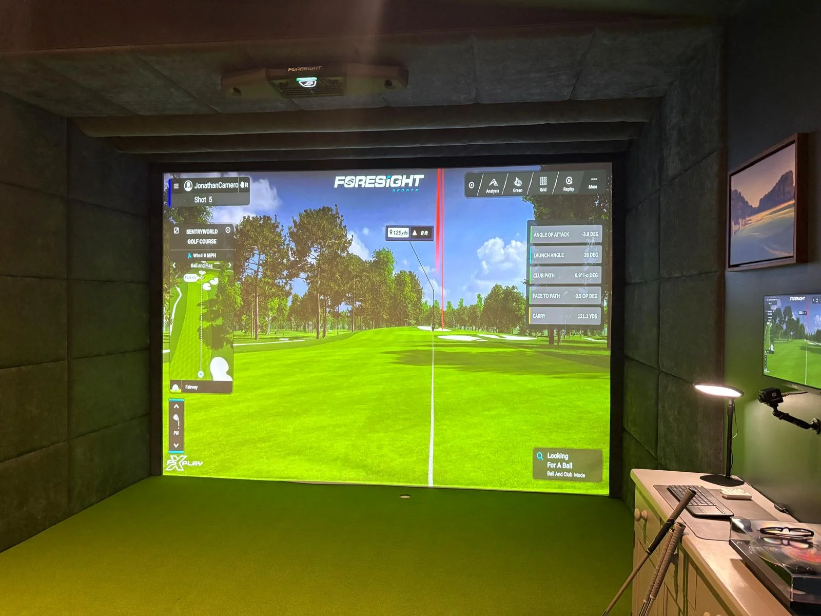 Golf simulator studio — lounge area with sofa and framed golf course prints